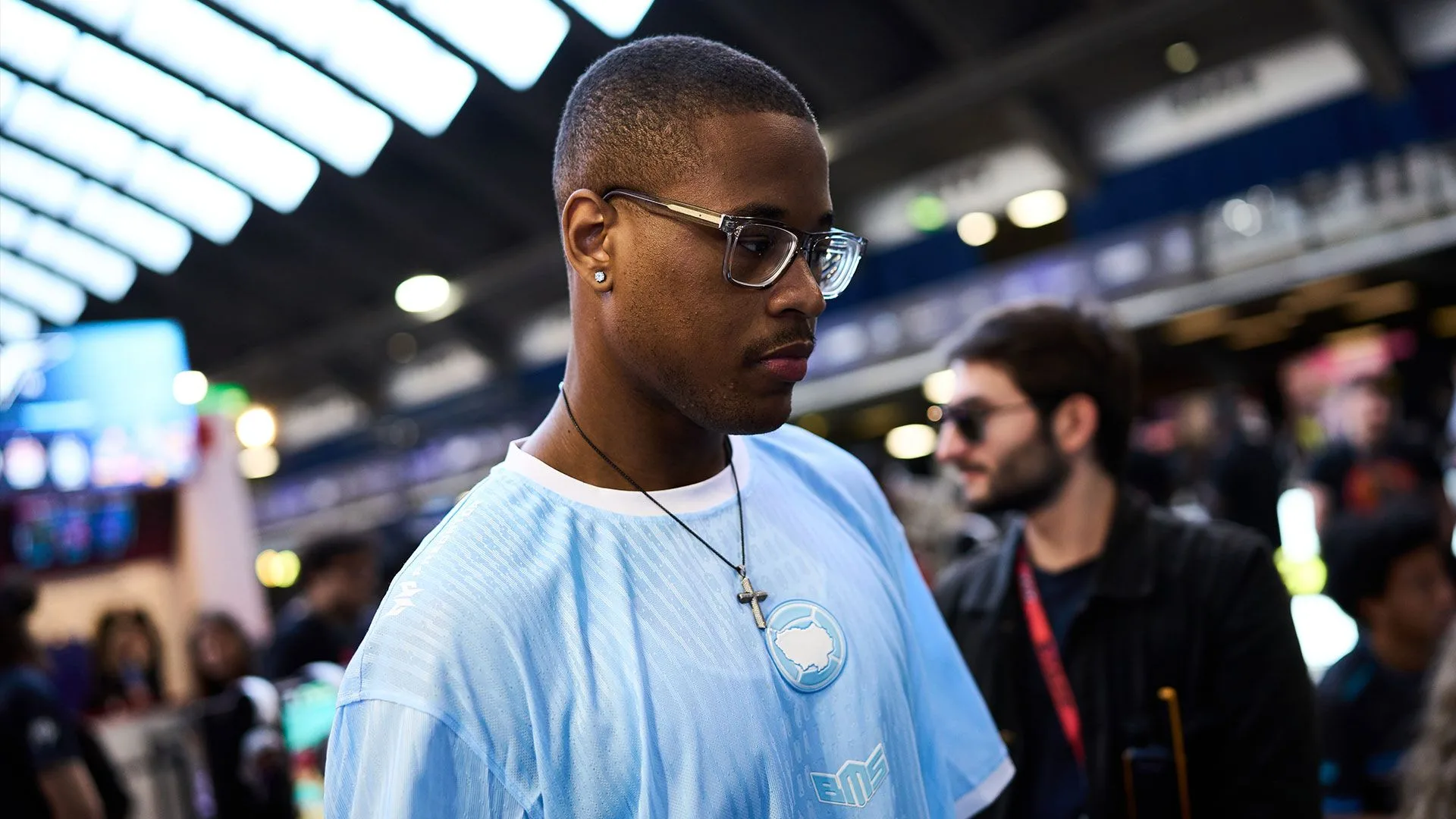International fighting game competition ahead of Evo France 2026 Competitive fighting game player wearing glasses and a light blue shirt at an esports event