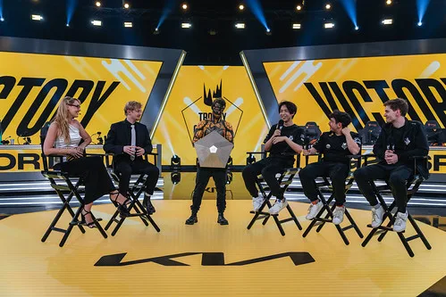 LEC stage with bright lights, team desks, and central screen LEC stage with bright lights, team desks, and central screen