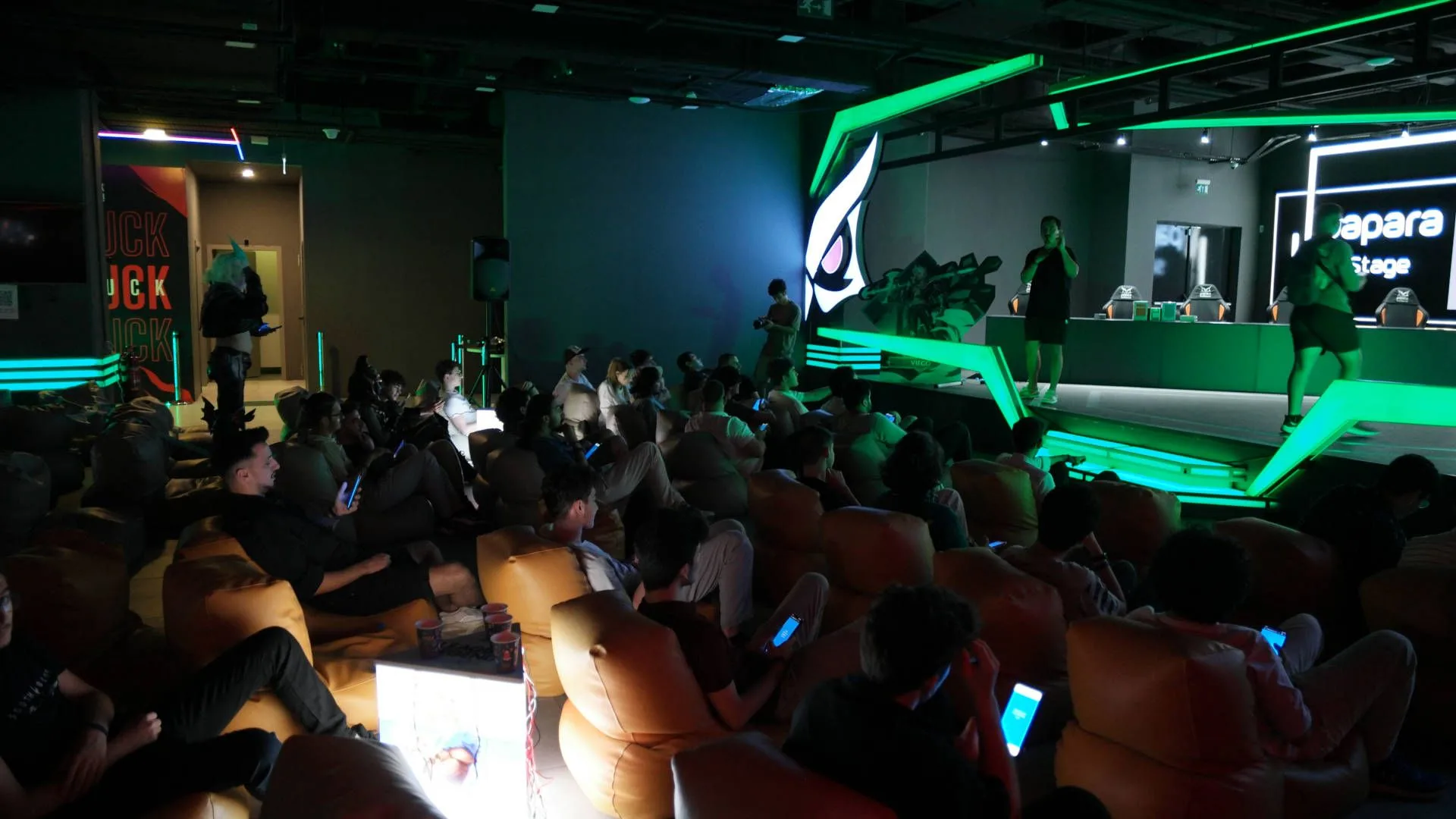 Wild Rift organized-play community event Audience gathered inside a gaming event venue with illuminated green esports stage lighting during a previous Wild Rift organized-play event