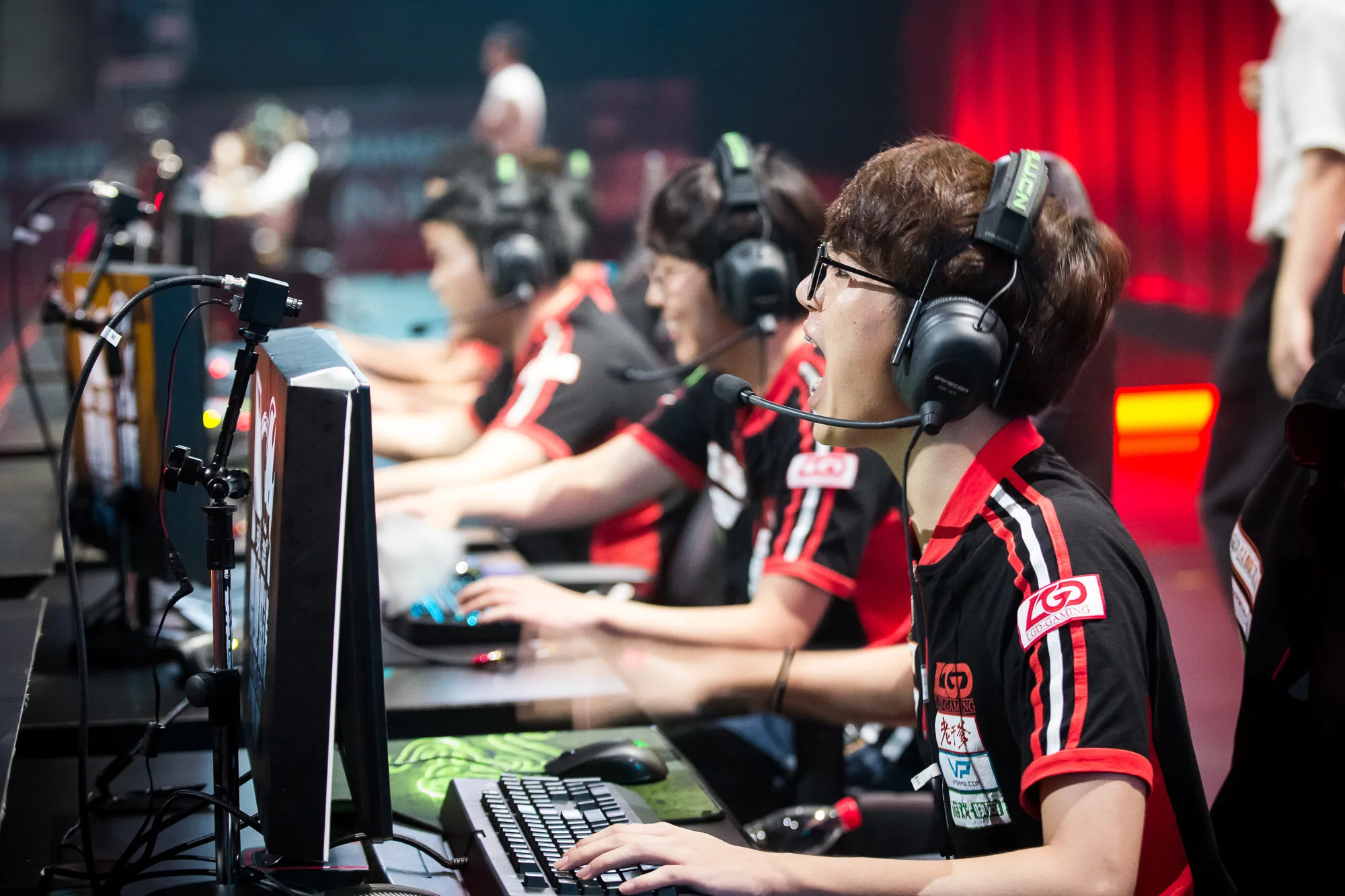 League of Legends players wearing headsets at a competitive stage League of Legends players wearing headsets at a competitive stage